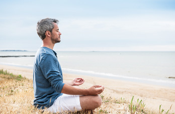 man meditating on beach